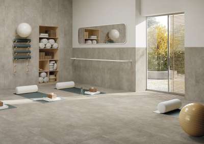 Helles Yoga-Zimmer mit hochwertigen Fliesen in Betonoptik an Boden und Wänden.