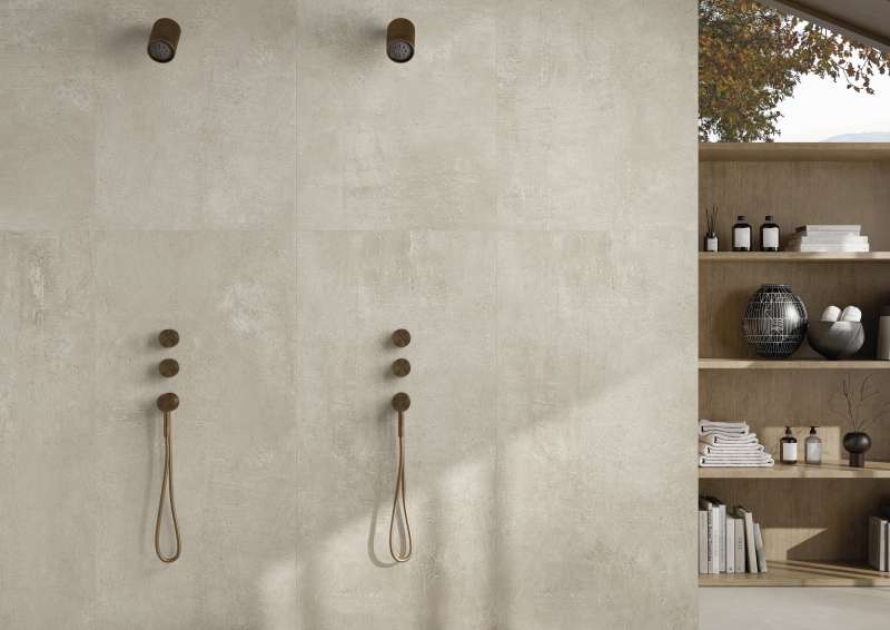 Helle, strukturierte Fliesen in einem modernen Duschbereich mit zwei Brausen und Regal.