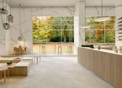 Modernes Interieur mit hellen Porcelaingres Fliesen an Boden und Wänden, großer Fensterfront zum Park.