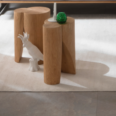 Graue Bodenfliesen im Innenbereich, kombiniert mit hellem Teppich und Holzmöbeln.