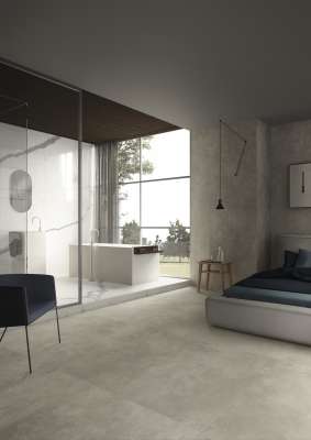 Helle Betonoptik-Fliesen im offenen Schlaf- und Badezimmerbereich.